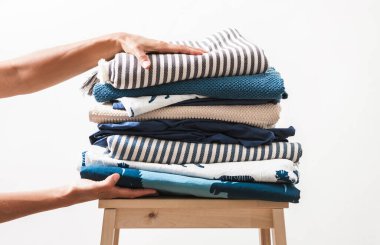 Kadın elleri bir yığın mavi ve bej çamaşır alır.