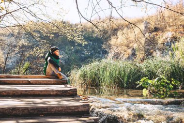Oğlan dağ gölünün üzerindeki tahta köprüde oturuyor.