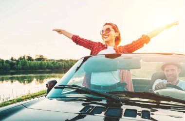 Aşık mutlu çift gün batımında Cabriolet arabasıyla gider.