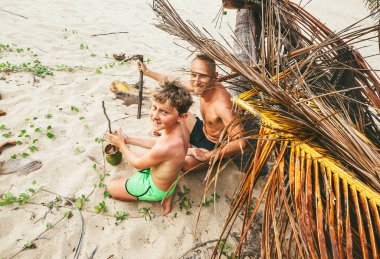Baba ve oğul Robinzone 'de oynuyorlar, ateş yakmaya çalışıyorlar.