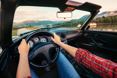 Sürücü elleri üstü açık araba direksiyonunda.