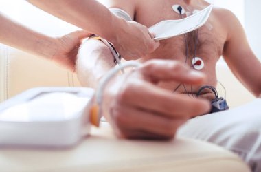 Holter monitör eliyle Sphygmomanometre ile test edilen adamı kapat