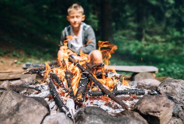 Çocuk kamp ateşinin yanında oturuyor. Yaz kampı zamanı