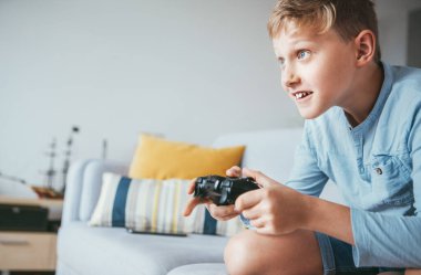 Genç çocuk oyun konsolunu hevesle oynuyor