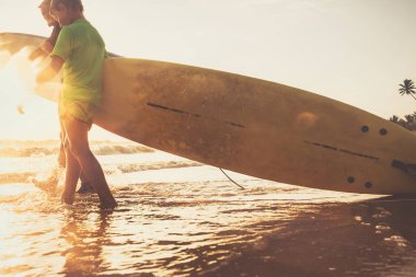 Oğul ve baba sörfçüler okyanus dalgalarında sörfçüler