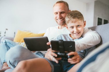 Elektronik aletlerle oynayan baba oğul portresi. Sıcak bir atmosferde evde oturmak.