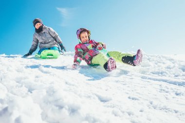 Erkek ve kız kardeşler kar yamacından aşağı kayıyorlar. Kış zevkleri
