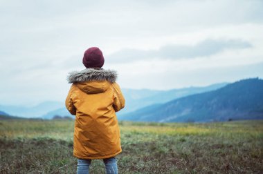 Sarı ceketli çocuk sonbahar vadisindeki panorame 'ye bakıyor. 
