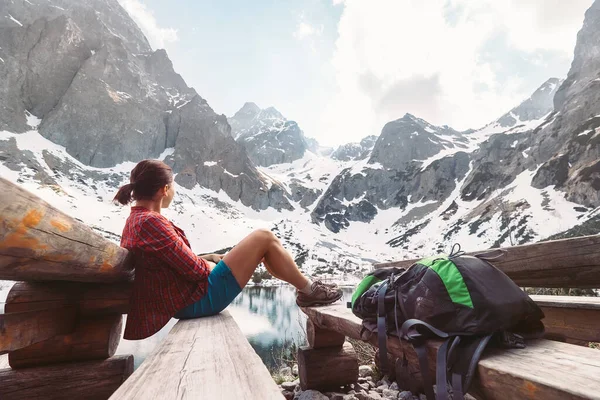 女旅行家坐在高山湖畔的休息点上 雪峰上尽收眼底 — 图库照片