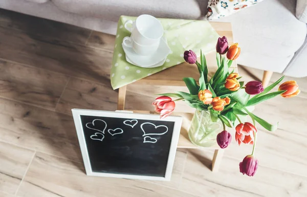 居心地の良い家庭春の雰囲気 カラフルなチューリップ チョークボードと木製の椅子の花瓶 — ストック写真