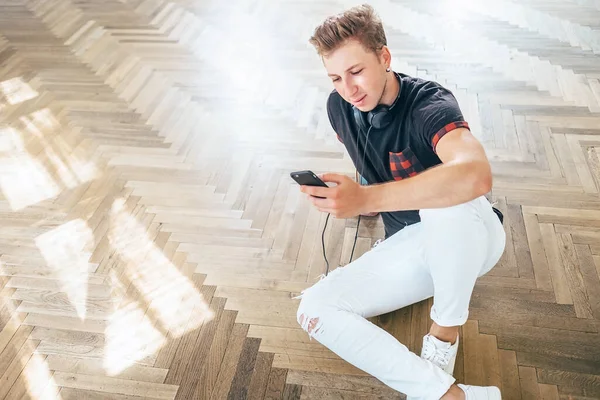 Giovane Utilizzando Smartphone Con Cuffie Ascoltare Musica Sedersi Sul Pavimento — Foto Stock