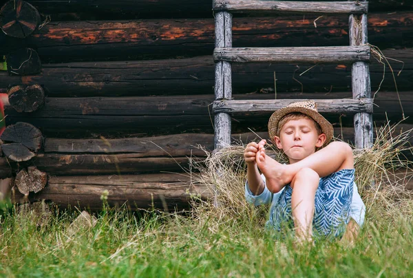 怠惰な少年は納屋の下の草の中にある 田舎の不注意な夏 — ストック写真