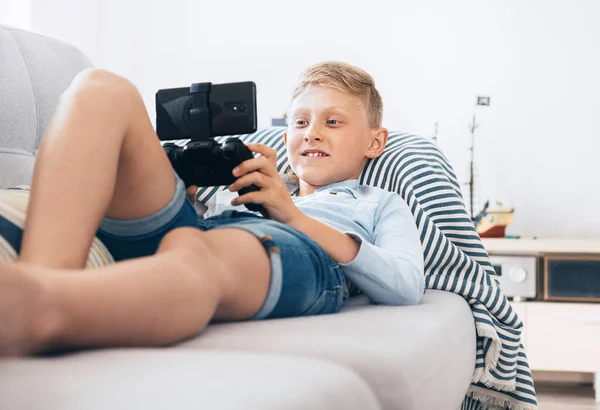 Niño Preadolescente Uso Gamepad Con Teléfono Inteligente Juega Juegos Acostado —  Fotos de Stock