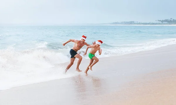 父と息子は大きな波から逃げる海のビーチで楽しい時間を過ごしています クリスマス休暇の時間だ 熱帯休暇 — ストック写真