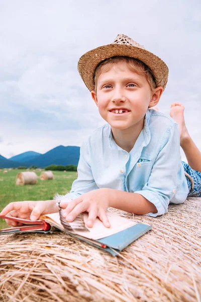 本のある少年は干し草のロールにある — ストック写真