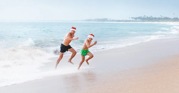 父と息子は大きな波から逃げる海のビーチで楽しい時間を過ごしています クリスマス休暇の時間だ 熱帯休暇 — ストック写真