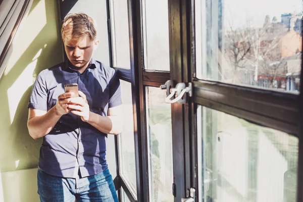 Hombre Joven Con Teléfono Móvil Permanecer Cerca Ventana Contraste Luz — Foto de Stock