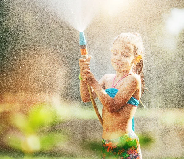 Cute Little Girl Posypuje Wodą Dla Siebie Węża Sprawia Deszcz — Zdjęcie stockowe