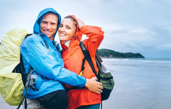 Feliz Casal Viajantes Sorridentes Dia Chuvoso Praia Oceano — Fotografia de Stock
