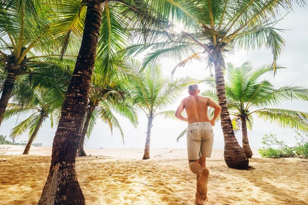 Uomo Corre Sotto Palme Verso Spiaggia Sabbia Dell Oceano — Foto Stock