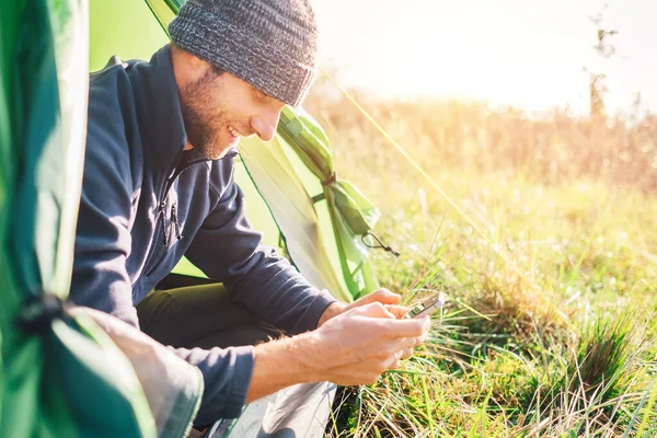 男人用手机在野外野营帐篷里的肖像画 — 图库照片