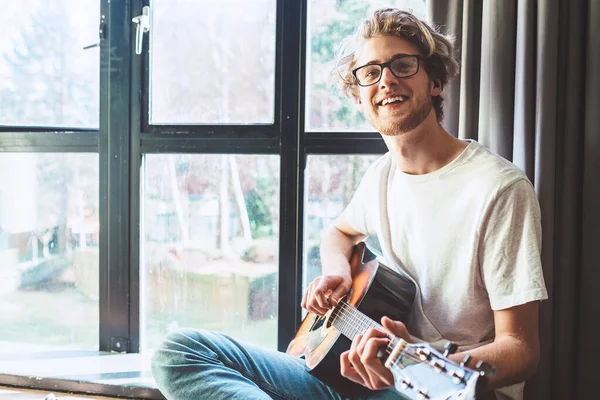 Jovem Sorridente Feliz Tocar Guitarra Perto Janela — Fotografia de Stock