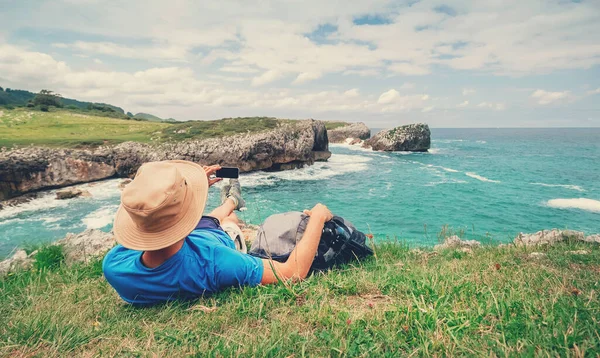 背包客在岩石的海滨休息 拍下美丽的海景 — 图库照片