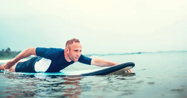 Man padding to line up on the surf board