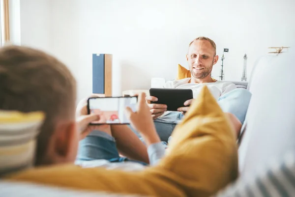 爸爸和儿子坐在客厅里玩平板电脑和游戏垫 — 图库照片
