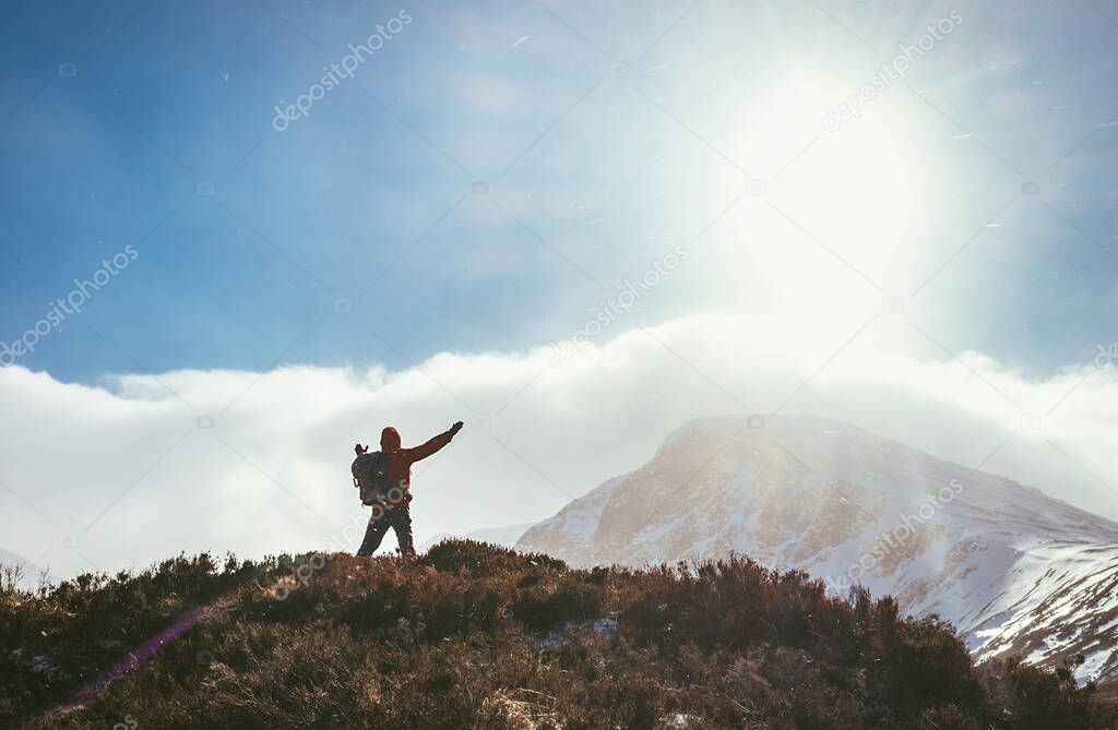 Mountain hiker greeting the sun in Highland