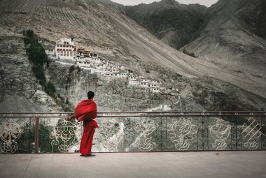 Kırmızı cüppeli Budist keşiş Diskit Manastırı, Hint Himalaya 'ya bakıyor.