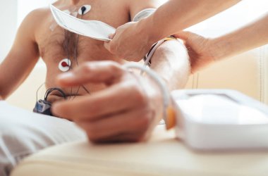 Holter monitör eliyle Sphygmomanometre ile test edilen adamı kapat