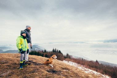 Bahar erken - baba oğul dağ tepelerinde köpekle yürür 