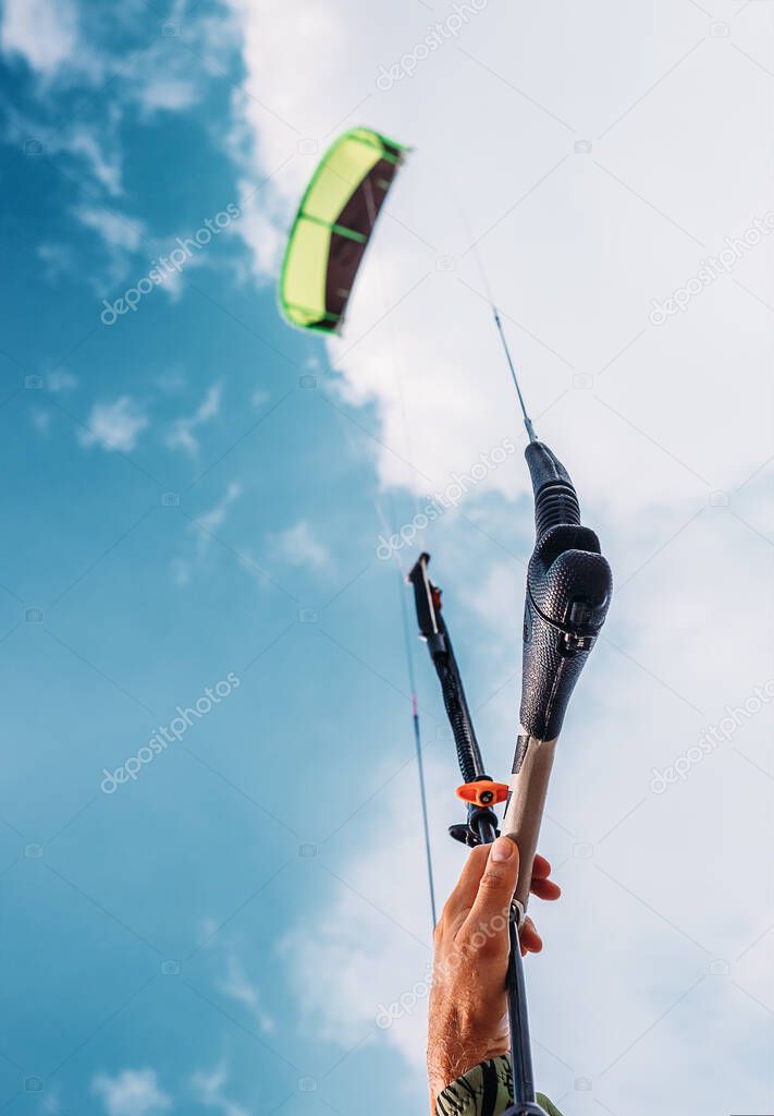 Close up image kitesurfer's hand with kite in blue sky