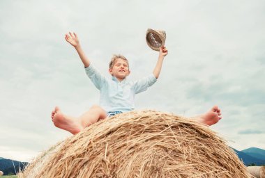 Mutlu çocuk büyük bir samanlıkta oturur.