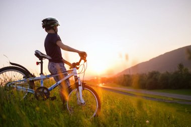 Bisikletli küçük çocuk günbatımının tadını çıkarıyor 