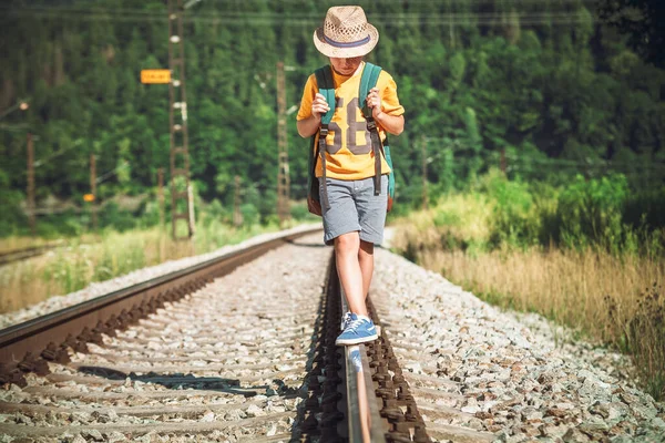バックパック付きの小さな男の子は鉄道線路を歩く — ストック写真