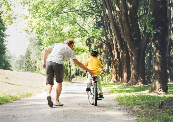 父は息子が自転車に乗るのを助ける — ストック写真