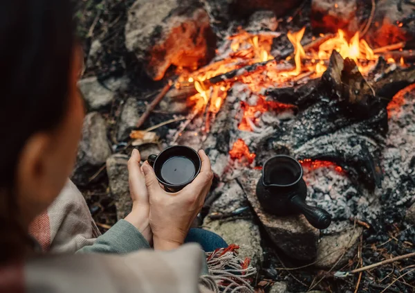 女性はキャンプファイヤーの近くでコーヒーを飲む — ストック写真