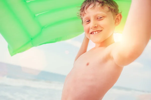笑男孩海景与绿色空气游泳床垫 — 图库照片