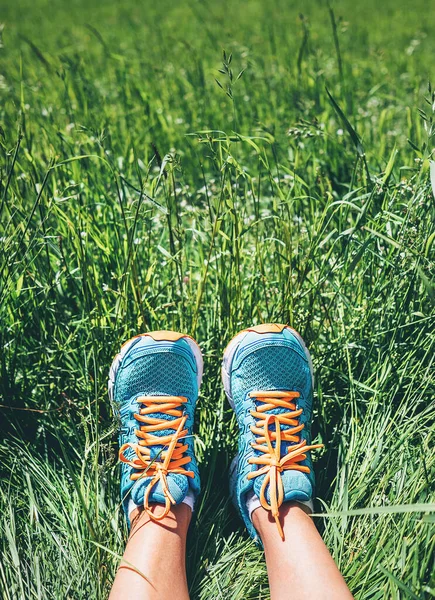 明るい青ランニングシューズの女性の足は高い緑の草の中にあります — ストック写真