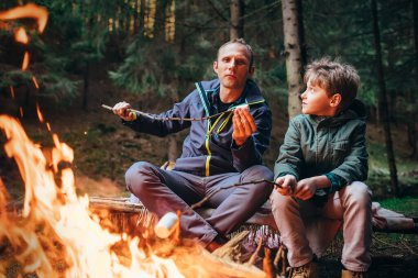 Ormanda piknik - baba ve oğul kamp ateşinde marshmallow