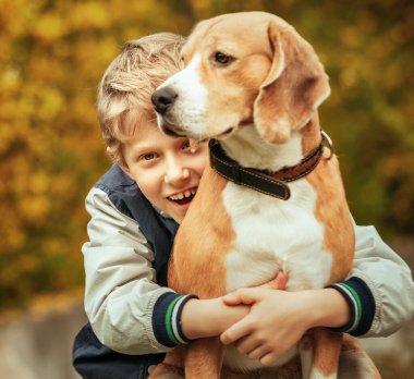 Mutlu gülümseyen çocuk en iyi köpeğine sarılıyor. 