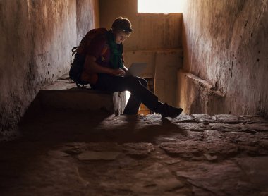 Turist adam internette dizüstü bilgisayarla eski Tibet kalesinde sörf yapıyor.