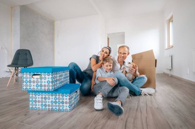 Mutlu aile yeni evlerinde yerde oturuyor. 