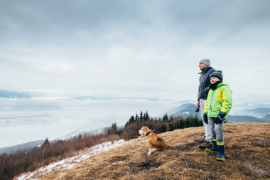 Bahar erken - baba oğul dağ tepelerinde köpekle yürür 