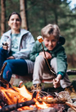 Çocuk kamp ateşinde kavrulmuş marşmelov gösteriyor.