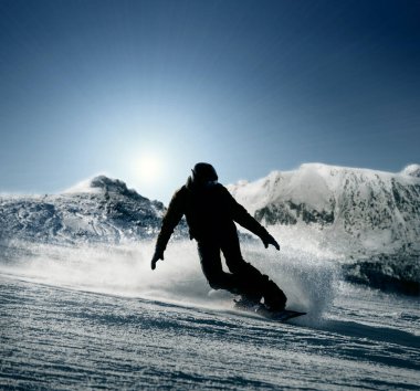 Snowboardcu karlı tepeden aşağı kayıyor
