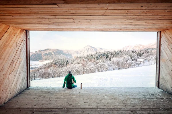 Man Sitter Trä Hangar Med Utsikt Över Snöig Bergsdal — Stockfoto