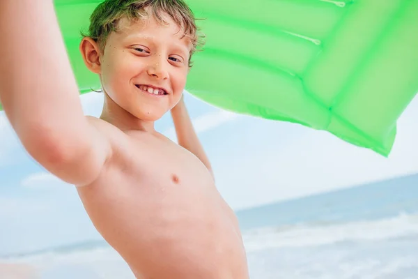 笑男孩海景与绿色空气游泳床垫 — 图库照片